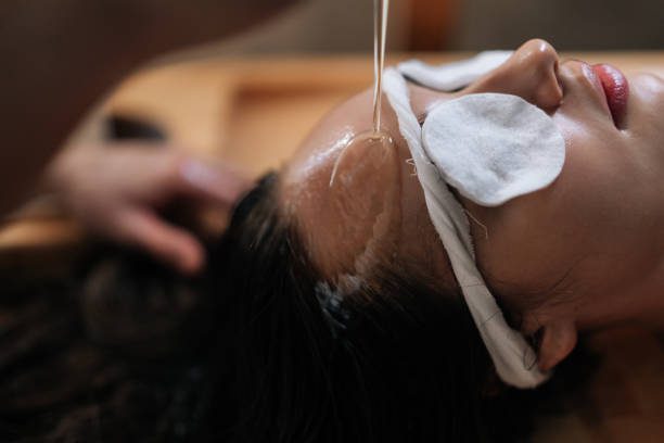Person receiving forehead oil spa treatment