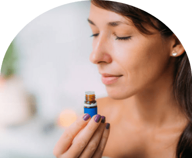 Woman smelling essential oil bottle, eyes closed
